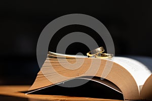 Two wedding rings are placed on the open Bible placed on the table as wedding rings prepared for lovers to wear and read Bible