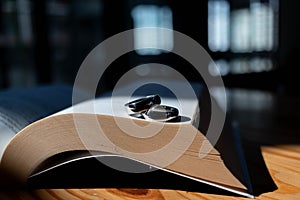 Two wedding rings are placed on the open Bible placed on the table as wedding rings prepared for lovers to wear and read Bible