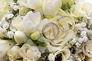 Two wedding rings on white roses bouquet