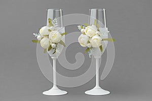 Two wedding wine glasses decorated with lace and white roses.