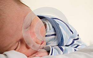 Two weeks old newborn baby boy sleeping on white sheet