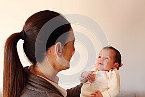 Two weeks old smiling little baby hold by his mother`s hands