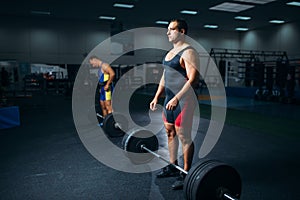 Two weightlifters doing exercise with barbells