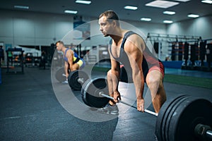 Two weightlifters doing exercise with barbells