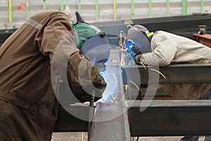 Two welder are welding steel structure with all safety equipment in factory