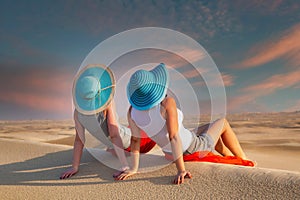 Two wemen on vacations at the sandy desert at sunset, UAE