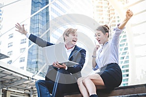 Two western business men and women sit and talk on the outdoor stairs