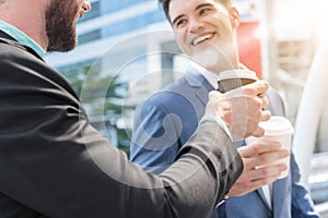 Two Westerner Business men talk with paper cup of hot coffee in