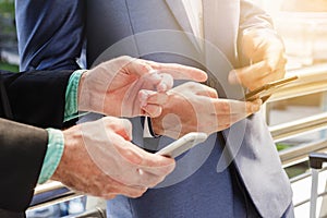 Two Westerner Business men talk and use smartphone with paper cu