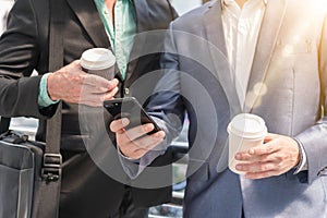 Two Westerner Business men talk and use smartphone with paper cu