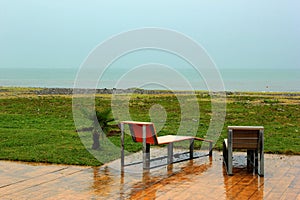 Two wet chairs on empty beach at rainy day in Batumi, Georgia