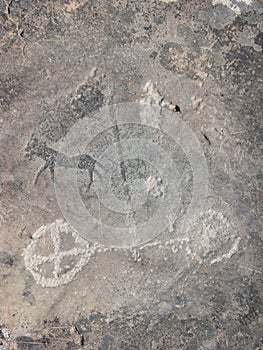 Two-wheeled cart and animal silhouette petroglyph