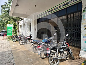 Two wheeler motor bike and scooty parked outside the government school and office building.