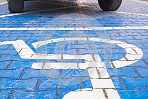 Two wheels on the disabled dedicated parking place marked with blue wheel chair symbol