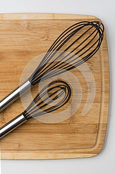 Two Whisks Angled on a Wooden Cutting Board