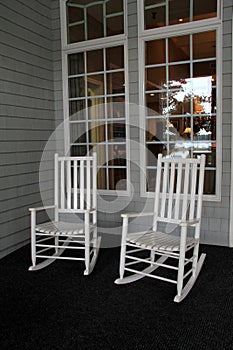 Two white Adirondack rocking chairs on front porch