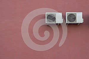 Two white air conditioner radiators on a red granular concrete wall. rough surface texture