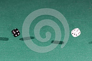 Two white and black dices falling on a green table