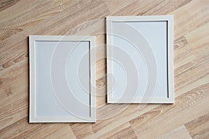 Two white blank frames on the wooden background. Mockup concept.