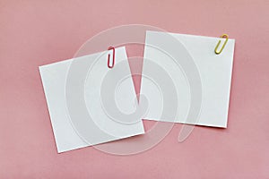 Two white blank note papers with clips on light pink background