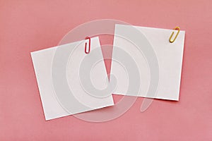 Two white blank note papers with clips on pink background