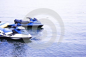 two white and blue jet skis on the pier by the sea