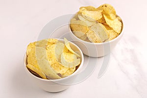 Two white bowls of tasty crispy potato chips