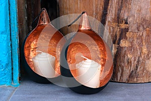 Two white candles on the shelf in spheric bronze shells.