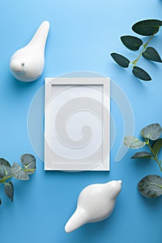 Two white ceramic birds, photo frame and green branches