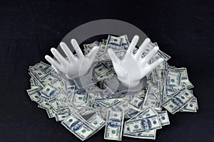 Two white ceramic hands with handcuffs on pile of 100 dollar notes