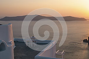 Two white chairs in a terrace for watching a romantic sunset landscape in the Mediterranean Sea in Santorini