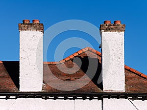 Two white chimneys on the roof against blue sky