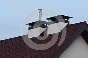 Two white concrete chimneys on a red black tiled roof