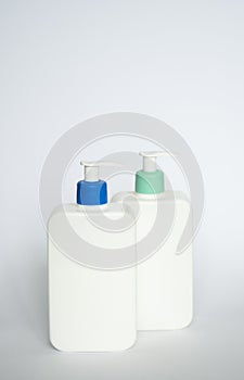 Two white cosmetic plastic bottle with pump dispenser pump and blue cap on white background. Liquid container for gel