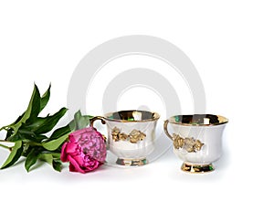 Two white cups with a gold handle and a flower