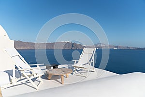 Two white deck chairs on rooftop deck overlooking Mediterranean