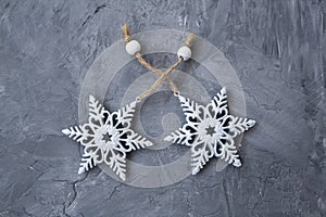 Two white decorations on a Christmas tree in the form of snowflakes lie on a gray concrete background. There is a place for a