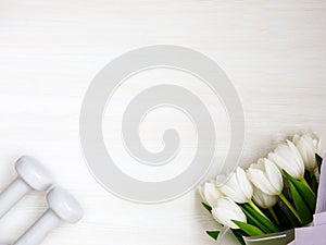 Two white dumbbells and tulips on white background with copyspace.