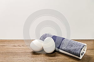 Two white eggs and a rolled towel lie on a wooden surface. Copy space.