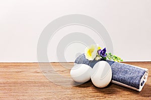 Two white eggs and a rolled towel lie on a wooden surface. Copy space.