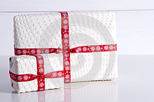 Two white gift boxes with polka dots a red ribbon.