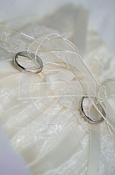 Two white gold wedding rings on white lace pad