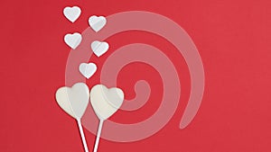 Two white heart shaped chocolates in love. A group of small hearts of symbols of love. Red background. Greeting card