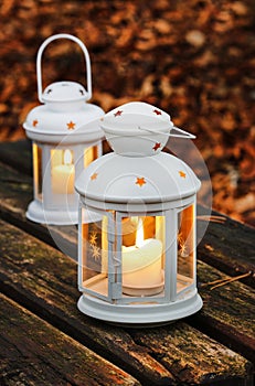 Two white lanterns on wooden bench