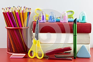 Two white and one red book and stationery on a red background