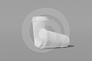 Two white paper mockup cups with a lid on a grey background. One cup vertically, the second horizontally on its side. 3D rendering