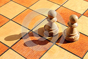 Two white pawns figures stands on a chess board