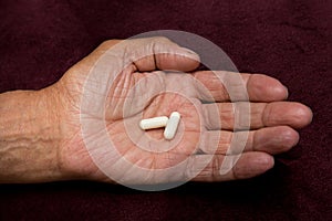 Two white pills in old men`s hands . Painful old age. Health care of older people