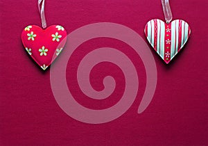Two white pink metal hearts on a dark pink paper background