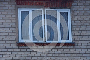 Two white plastic windows on a gray brick wall
